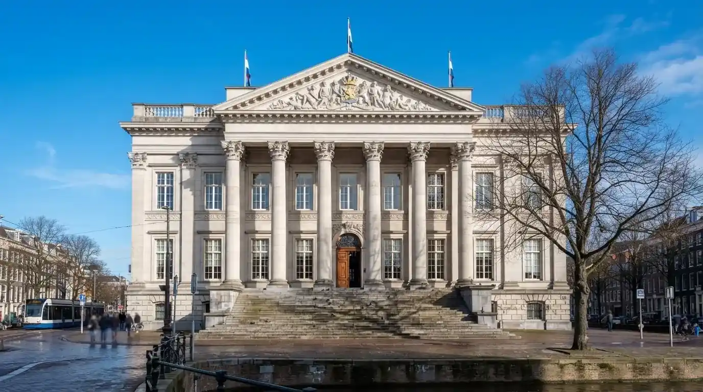 Een statig gerechtsgebouw met brede trappen en zuilen staat onder een heldere hemel in een Nederlandse stad.